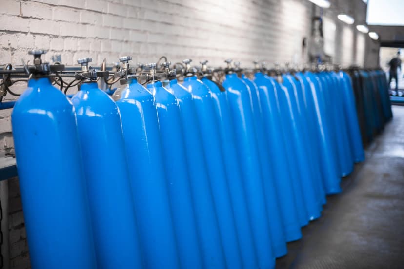 Array of Filled Oxygen Cylinders A line of blue oxygen cylinders secured to a wall rack.